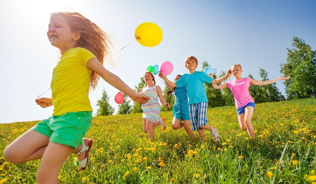 kids running on the grass with balloons on strings