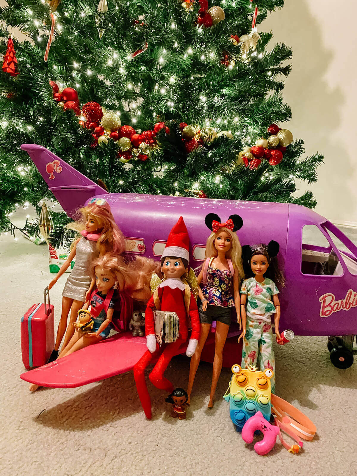 elf on the shelf going on holidays with barbies in front of barbie plane