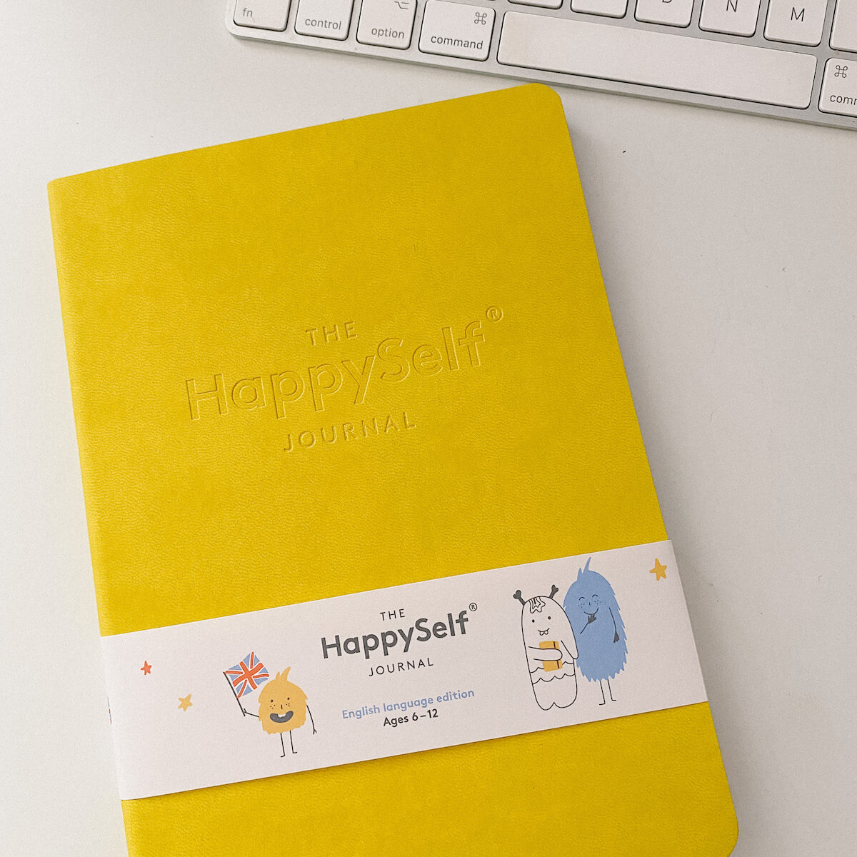 the happy self journal on desk with apple keyboard