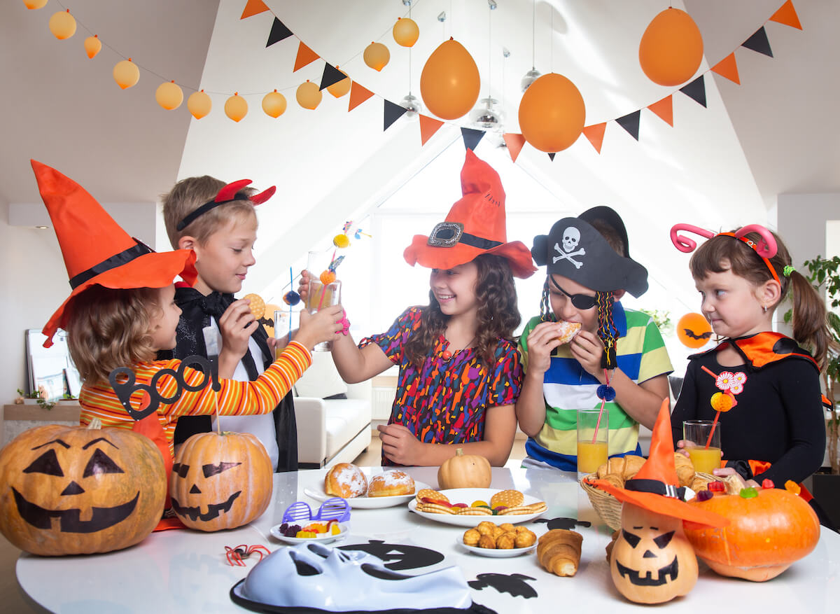 a group of kids at a Halloween food table dressed in halloween costumes