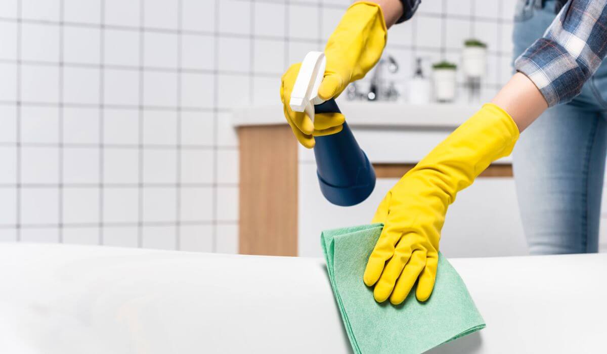 woman cleaning a bathtub with cloth