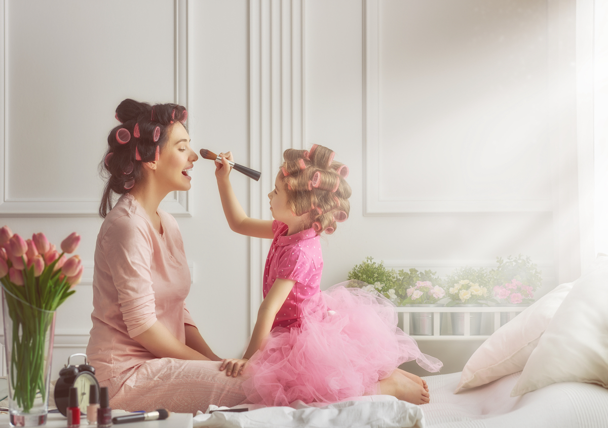 Mother and daughter doing makeup sitting on the bed