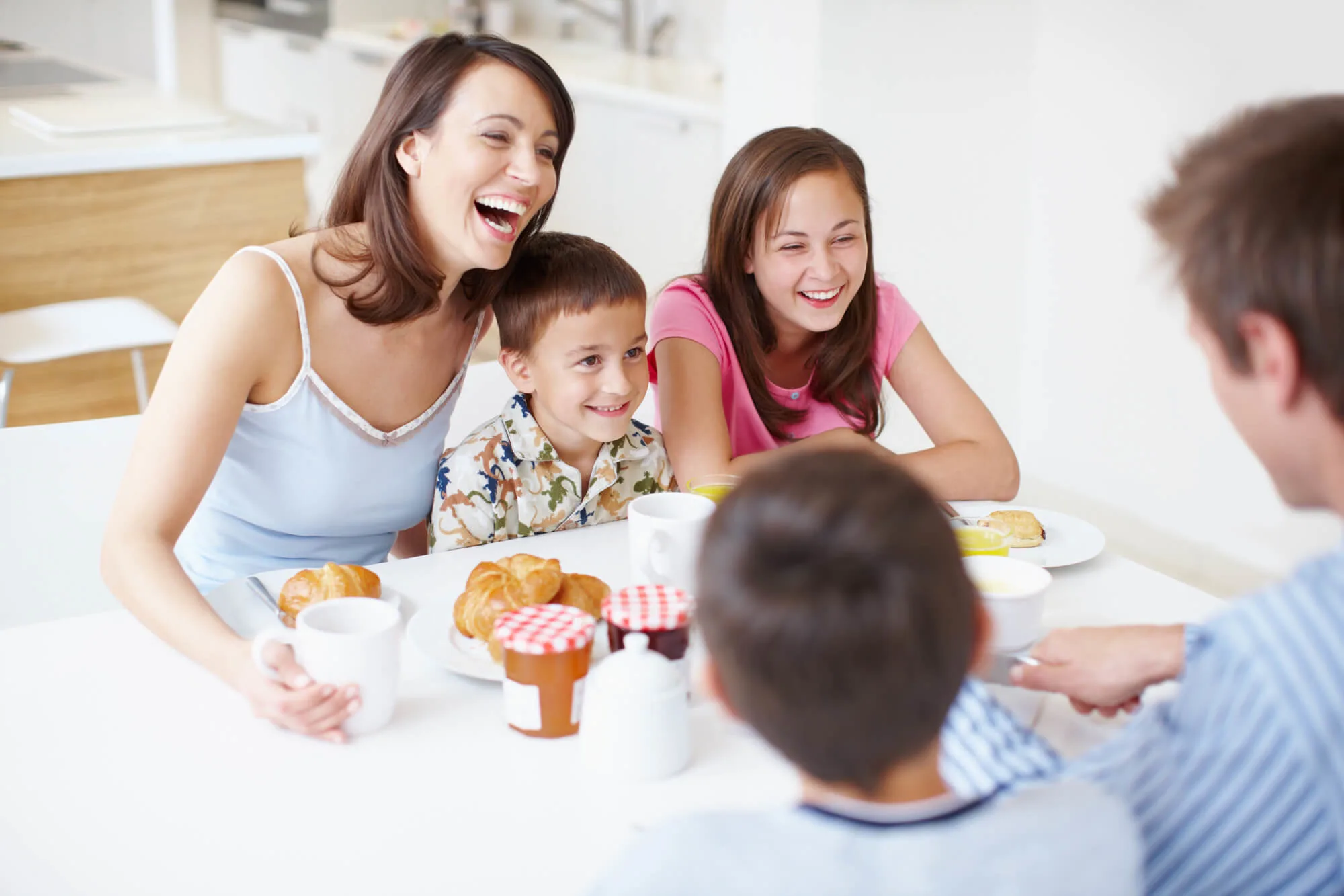 family with 3 kids eating breakfast and laughing together