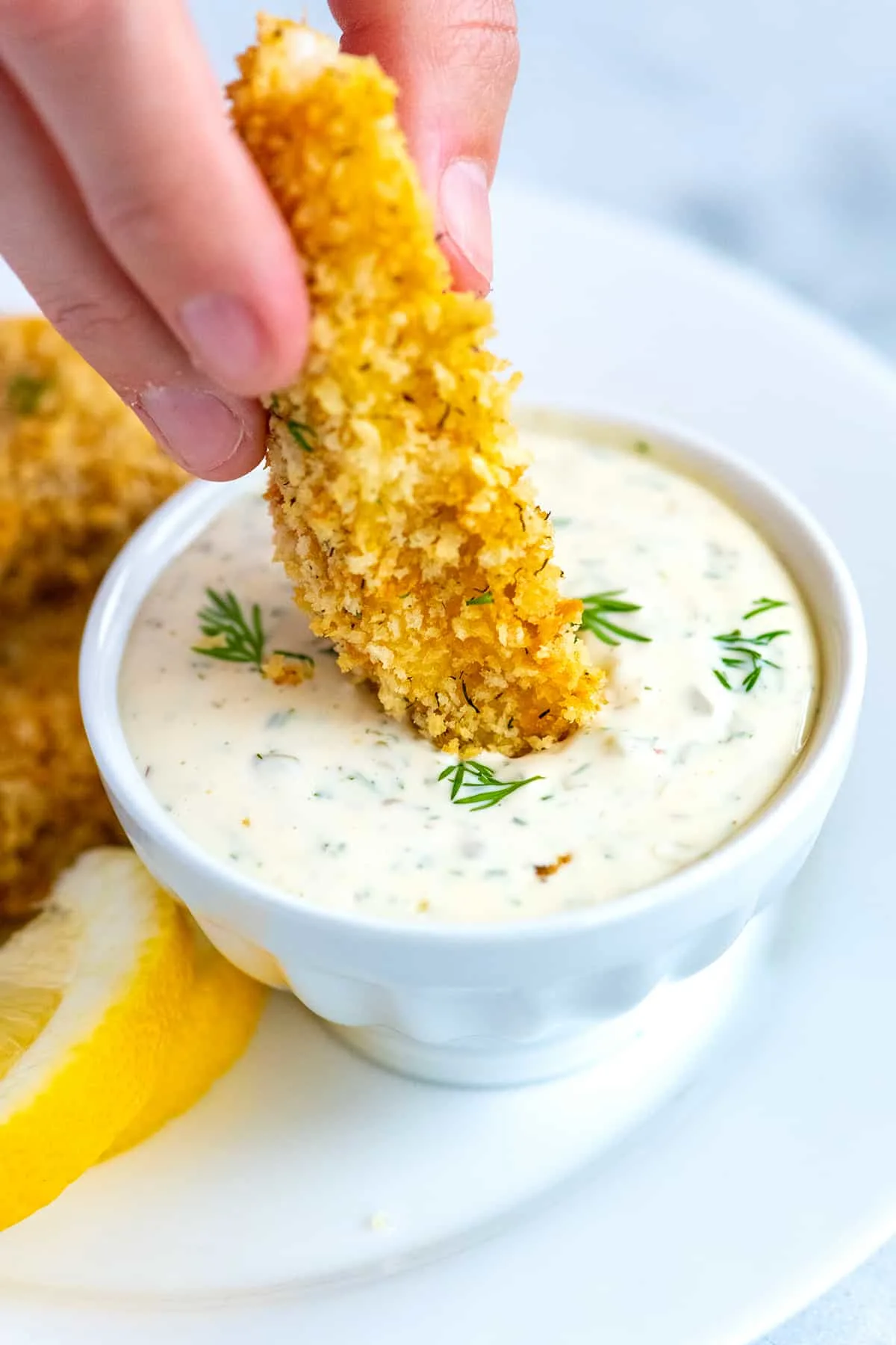 dipping chicken tender in homemade tartar sauce