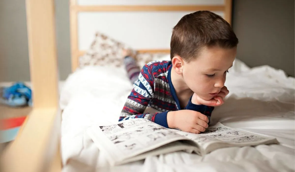 boy reading comic book on bed