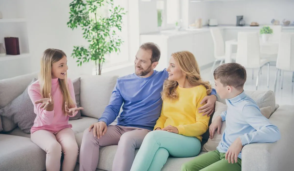 Family sitting on the couch while daughter tells a funny story